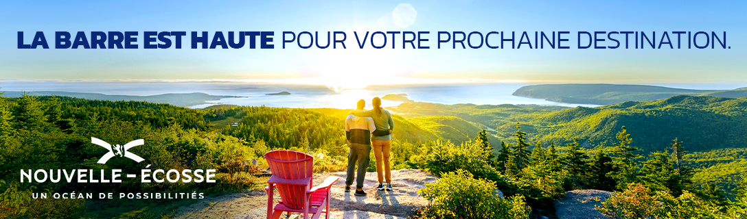 French billboard showing two people standing at the top of Franey Trail in Cape Breton Highlands National Park. Text reads les barre est haute pour votre prochane destination.